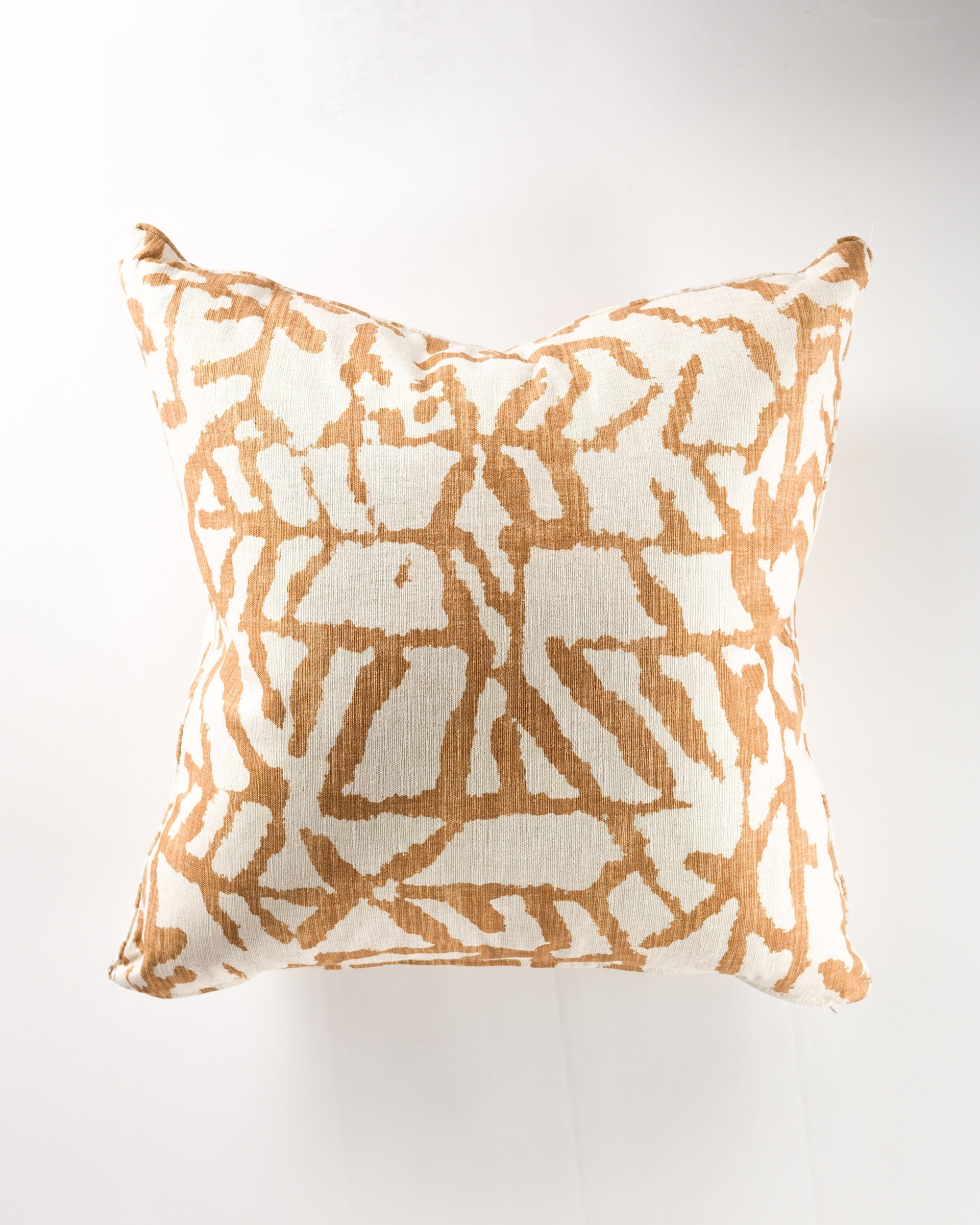 The Gabby Indigenous Camel Gr-5 Pillow 26x26 features a white background with an abstract tan pattern and a textured, woven look. Shown from above on a light surface. Pillow insert not included.