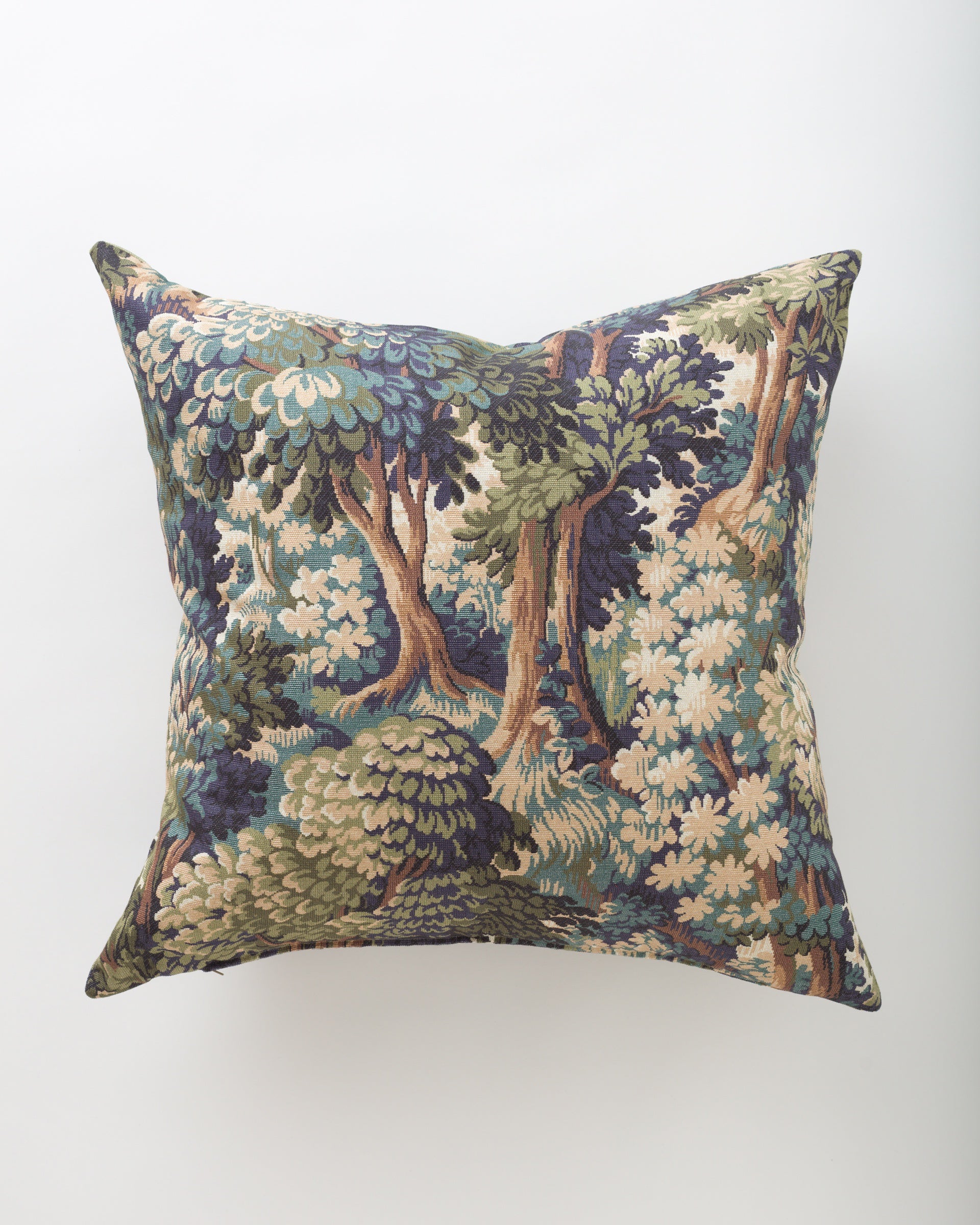 The Pindler Abbiente 26x26 is a square decorative pillow featuring a detailed tapestry design of trees and foliage in green, blue, beige, and brown on a white background. Includes a plush insert for comfort and support.