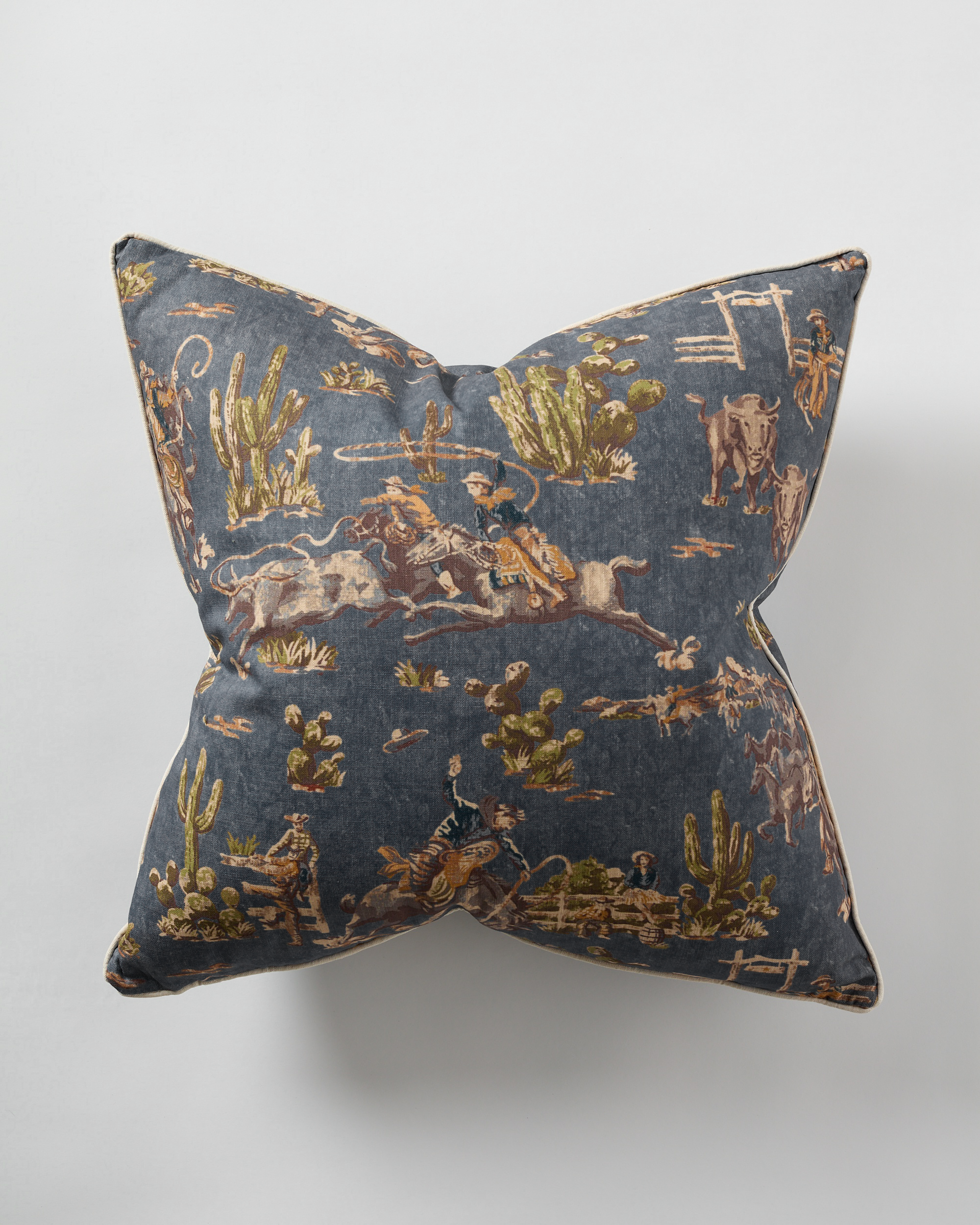 The Indigo Cowboy Pillow Jute 26x26 by Design Legacy features a dark indigo fabric with Western motifs—cowboys, horses, cacti, and cattle—on white. This custom accent adds rustic charm to your space.
