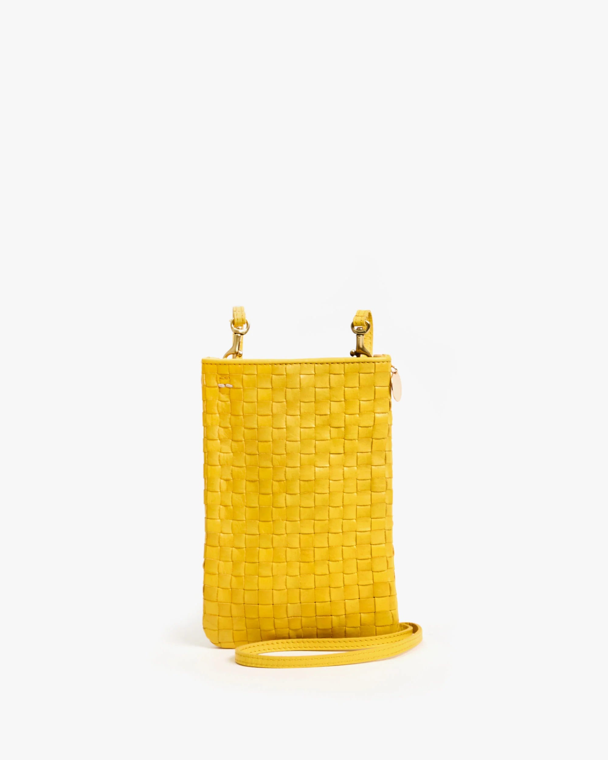 The Clare Vivier Poche is a small, rectangular yellow handwoven leather crossbody bag with a long strap and two metal clasps at the top, shown upright against a plain white background.