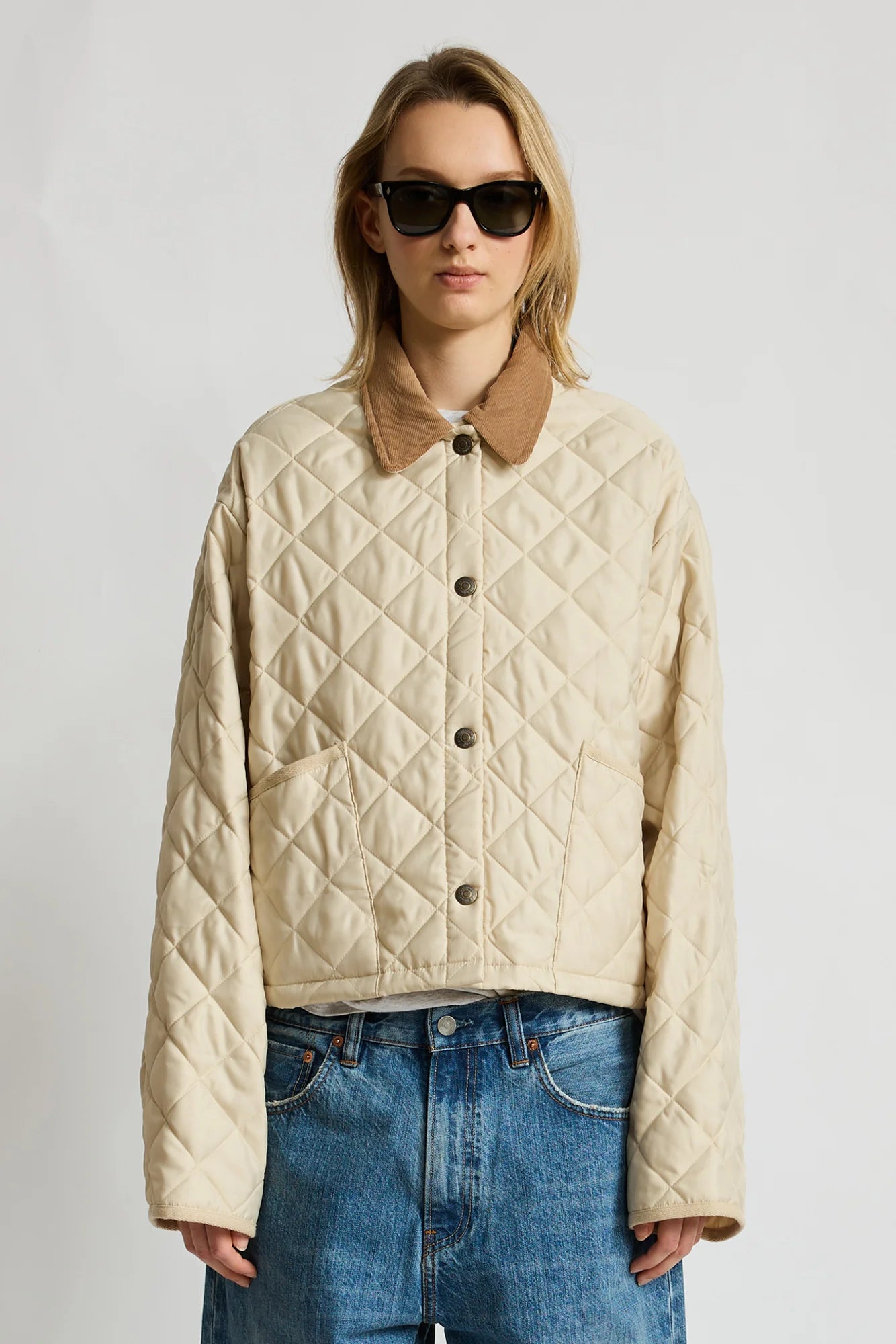 Denimist FAULKNER quilted jacket with snap closure and brown collar, styled with blue jeans and sunglasses.