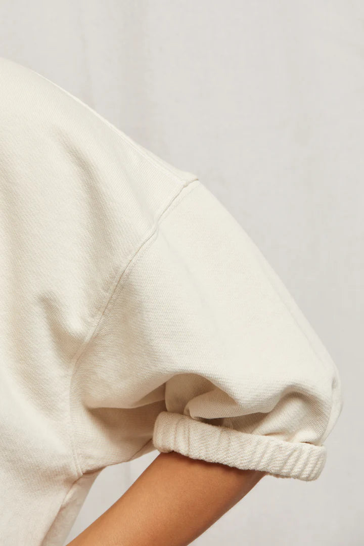 Close-up of a person wearing a light beige Rebecca 3/4 Puff Sleeve from Perfectwhitetee, crafted from soft French terry cotton. The image highlights the arm and part of the torso, showcasing the cozy texture against a plain background.