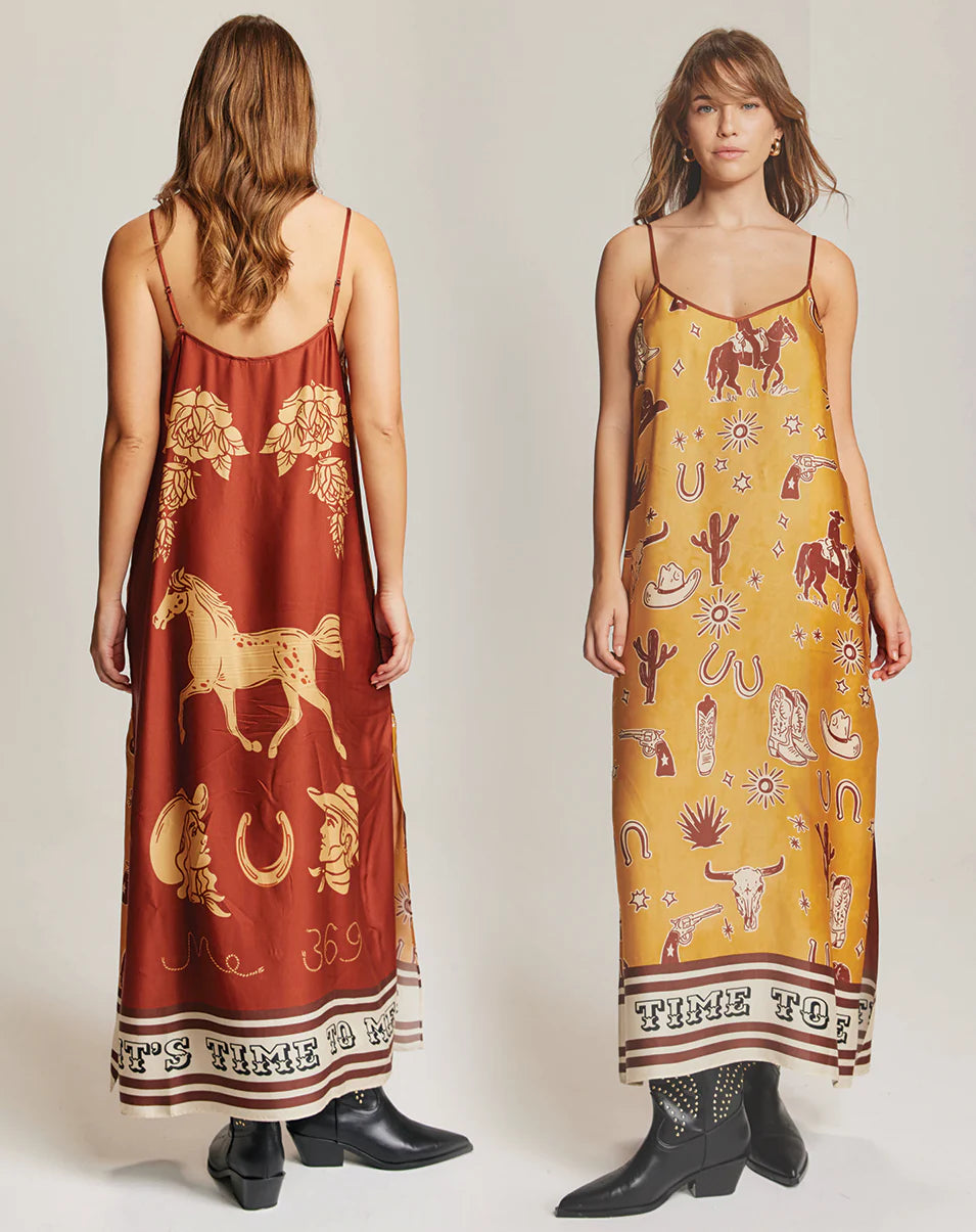 Two women wear Me369 Olivia Camisole Dresses—midi-length with thin straps and Western prints like horses, cacti, and horseshoes. Both pair them with ankle boots; a "Time to Ride" border finishes each dress.