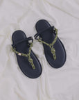 The Flowze FLO Sandals feature navy blue lightweight soles and green rope straps with adjustable knots, displayed on a soft white fabric background.