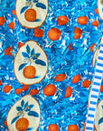 This vibrant stretch sateen fabric showcases an "Orange Grove" print with oranges and blue leaves, some encircled by beige ovals, and a striking white-blue striped border. It's perfect for crafting the stylish Powell Skirt by Hunter Bell NYC.