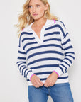 Someone is wearing Lisa Todd's blue and white striped cotton "Stripescape" sweater with pink shoulder accents and a polo collar, paired with blue jeans, on a plain white background.