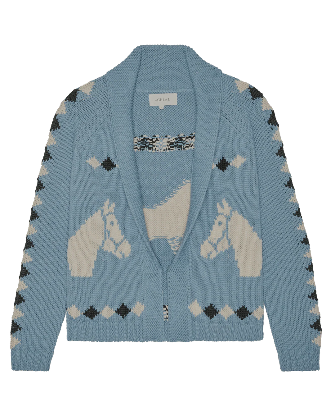 The Great Inc. Stable Lodge Cardigan is light blue with a shawl collar, cream western horse motifs on front and back, and geometric diamond patterns on the sleeves and hem.