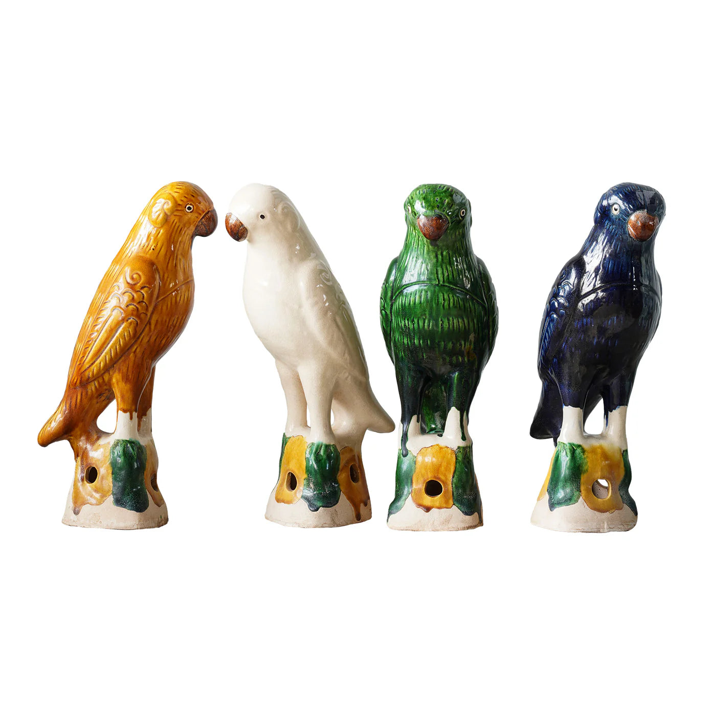 Blue Ocean Traders' Parrot Small features four hand-painted ceramic bird figurines—yellow, white, green, and blue—each perched on decorative bases with leaf patterns, inspired by Jingdezhen porcelain.