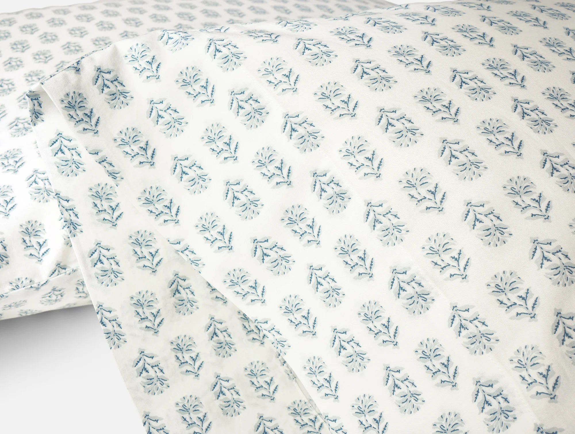 Close-up of Coyuchi Inc's Org Percale Pillowcase Dew Chrysanthemum S/2 Queen, made from 100% organic cotton with soft white fabric and evenly spaced, delicate light blue floral prints inspired by nature.