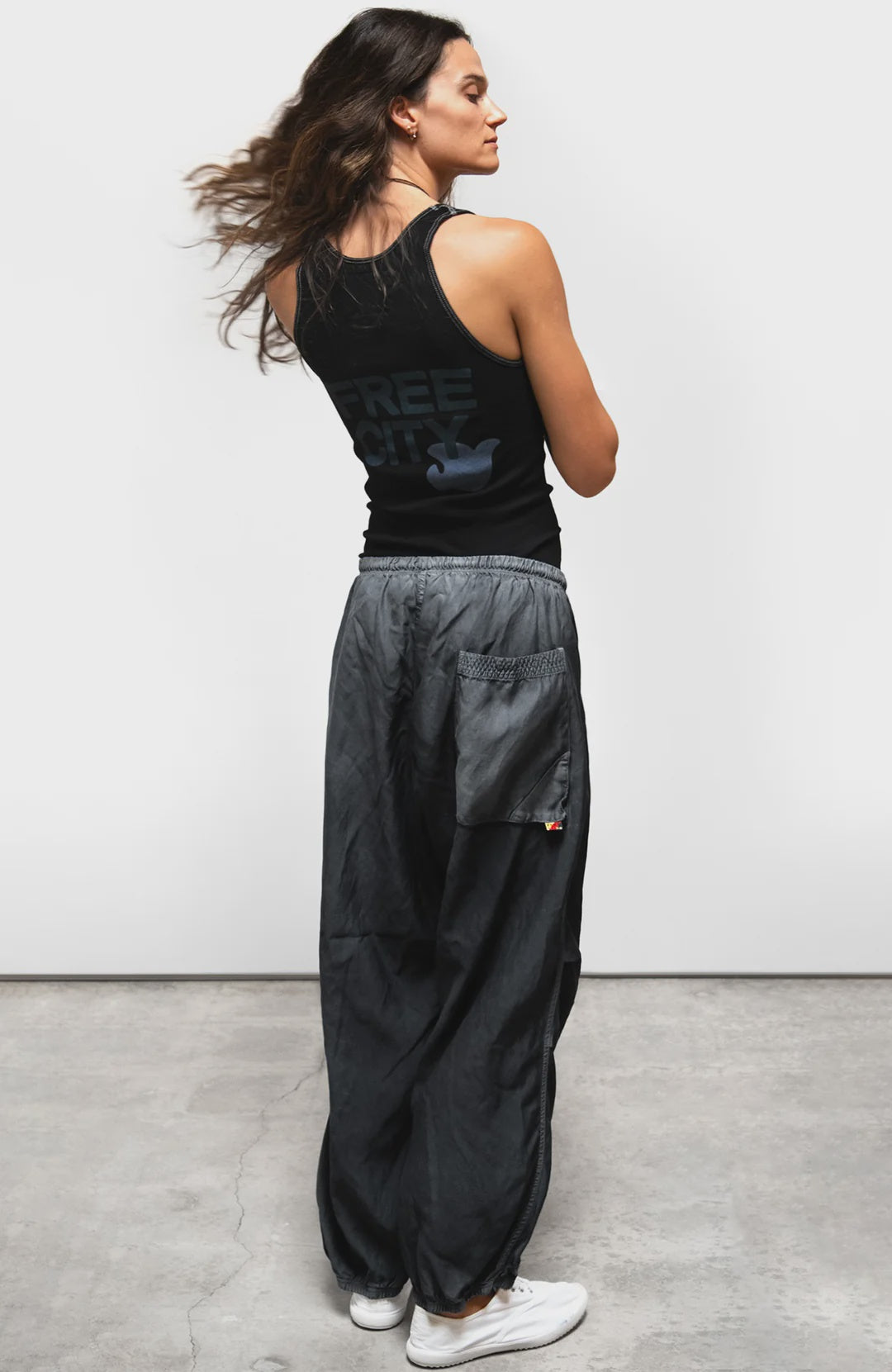 Free City Matte Satin Drawcord Biggy Pant in a relaxed fit, shown from the back, styled casually on concrete floor.
