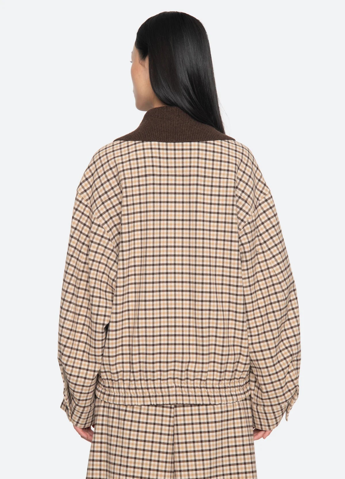 A person with long dark hair is seen from behind, wearing the Sea New York Savannah Plaid Jacket with a loose, modern fit and an oversized ribbed-knit collar against a plain white background.