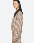 A woman with long, straight black hair poses in profile against a light gray background, wearing the Sea New York Savannah Plaid Jacket with a contemporary fit, matching pants, and an oversized ribbed-knit collar.