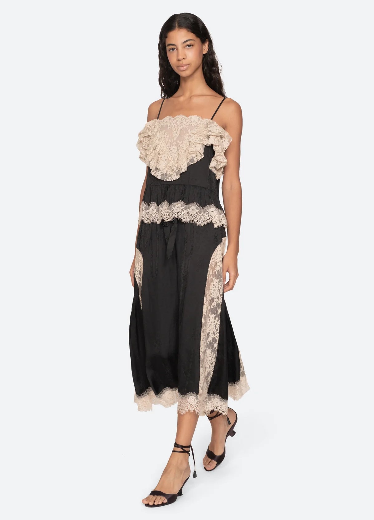 A woman wearing Sea New York's Ethel Solid Pants stands against a plain light background, paired with black heeled sandals.