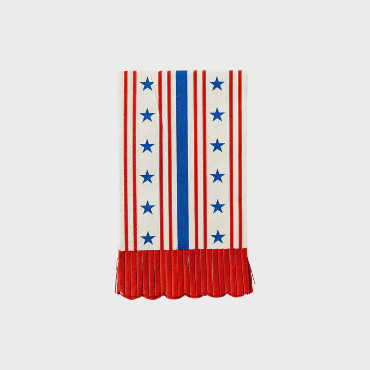 A white fabric with vertical red stripes and a central blue stripe lined with blue stars, reminiscent of My Mind's Eye Guest/Dinner Napkin. The bottom edge features a red, pleated fringe with a scalloped hem, resembling elements of the American flag.