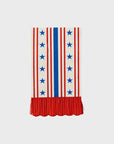 A white fabric with vertical red stripes and a central blue stripe lined with blue stars, reminiscent of My Mind's Eye Guest/Dinner Napkin. The bottom edge features a red, pleated fringe with a scalloped hem, resembling elements of the American flag.