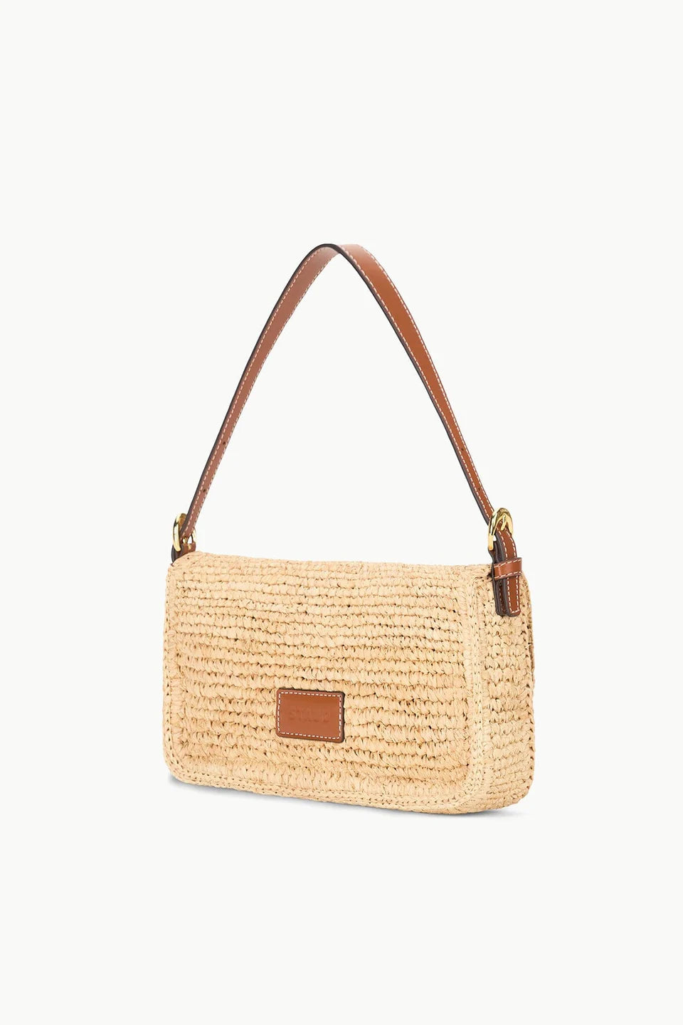 The Staud Harlow Raffia Bag in natural features a rectangular design with a brown leather shoulder strap and a small front leather patch, displayed against a white background.
