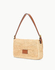 The Staud Harlow Raffia Bag in natural features a rectangular design with a brown leather shoulder strap and a small front leather patch, displayed against a white background.