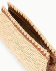 A close-up of the Staud Maude Convertible Clutch /Natural shows its raffia body, brown leather trim, inner zipper, and a leather strap for versatile clutch or shoulder wear.