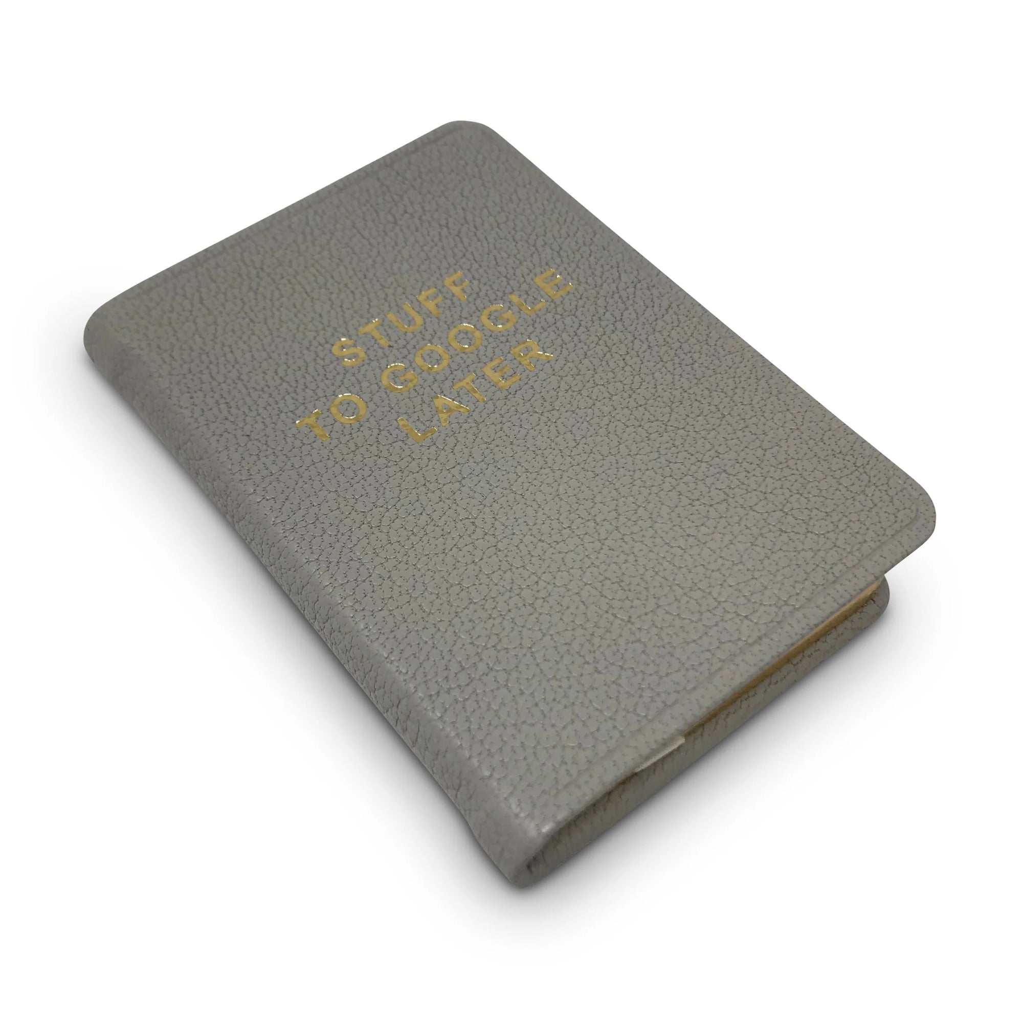 A compact gray goatskin leather Mini Notebook by Kempton & Co. features a textured cover with gold embossed "STUFF TO GOOGLE LATER" and is shown against a white background.