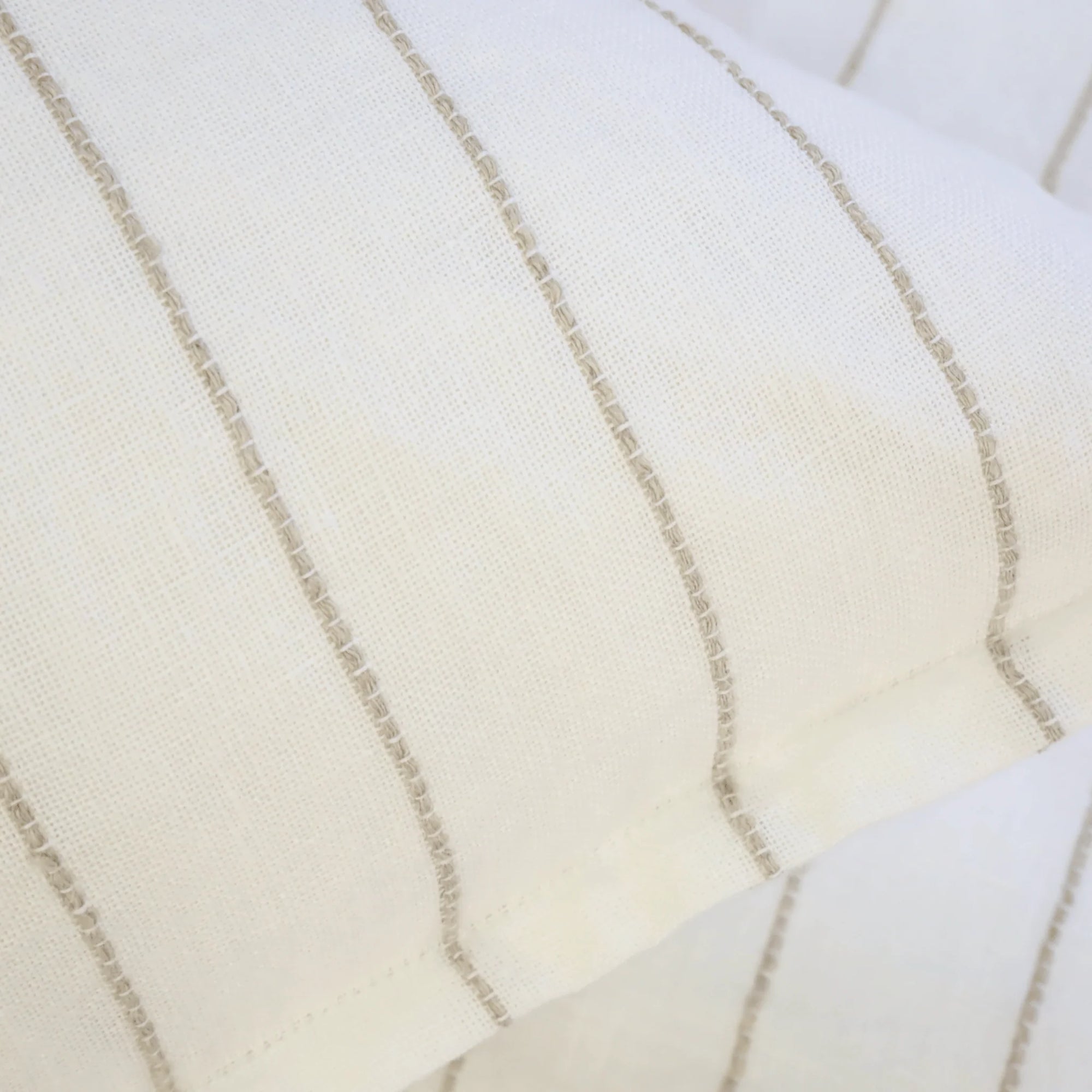 A close-up of two overlapping Blake Big Pillows 28x36 from POM POM, showcasing sophisticated stripes with vertical, thin beige lines that form a simple and elegant pattern.
