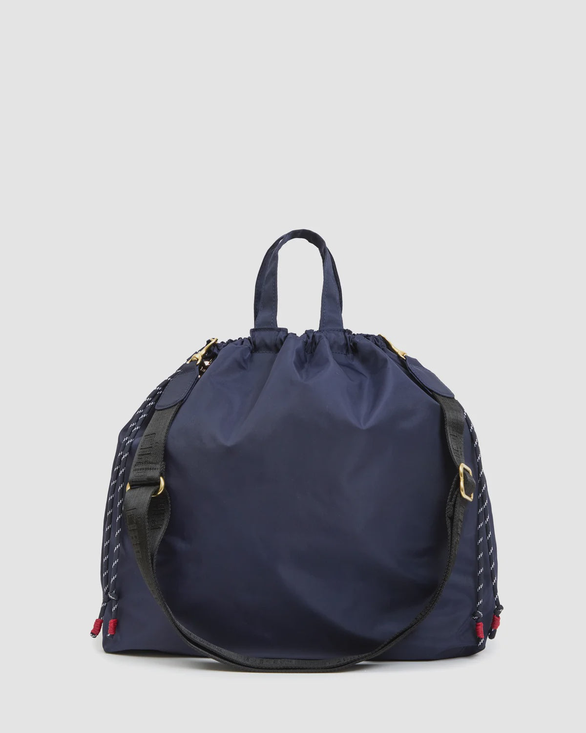Large navy tote with black crossbody strap, gold hardware, and red accents by Clare Vivier.