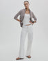 A woman stands against a plain background wearing Rag & Bone's ftwt saige full straight white jeans, a gray checked open shirt over a white tank top, and brown sandals. Her hair is pulled back and one hand rests on her hip.