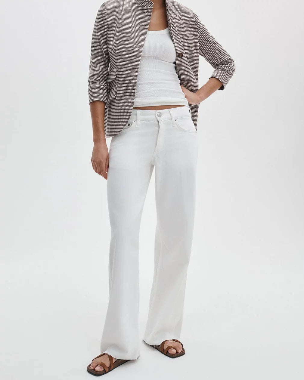 A person wearing Rag & Bone ftwt saige full straight jeans, a brown and white striped blazer, a white tank top, and brown sandals stands against a plain white background.