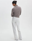 A person stands with their back to the camera, wearing Rag & Bone's ftwt saige full straight jeans and a brown and white striped long-sleeve top, hands on hips, against a plain white background.