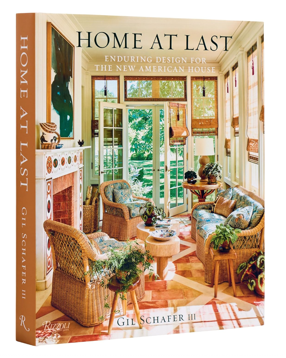 Cover of the book &quot;Home at Last: Enduring Design for the New American House&quot; by Gil Schafer III, featuring a cozy, sunlit room with Bungalow-style wicker furniture and plentiful greenery, published by Random House.