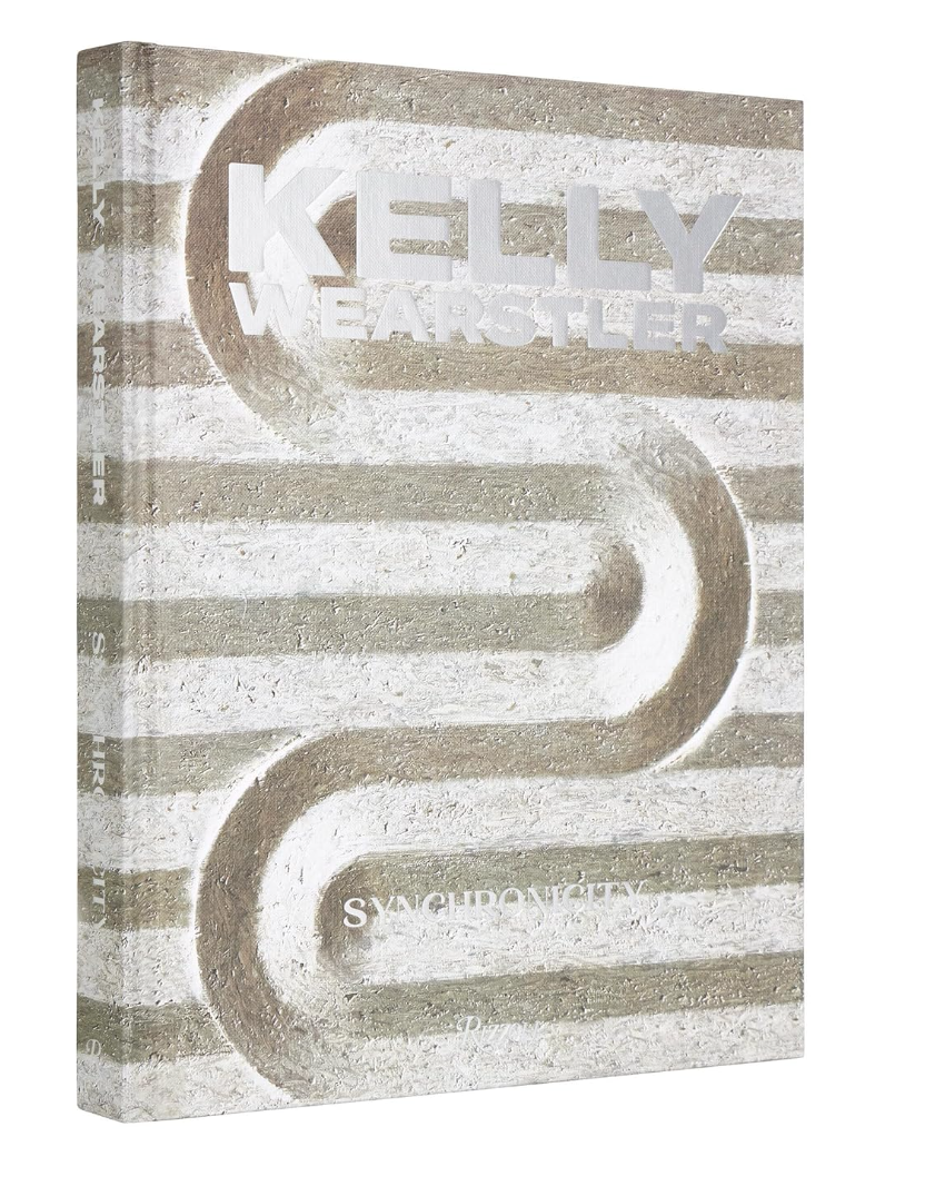 A book cover featuring the title "Kelly Wearstler: Synchronicity" by Random House, embossed on a background with white and gray striped patterns influenced by Arizona style. The text and design elements have a tactile, textured appearance.