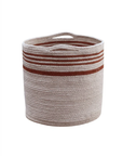 A round, woven storage Basket Twin with practical handles near the top. It is primarily beige with three horizontal reddish-brown stripes near the upper section. The basket has a simple and rustic design, suitable for organizing or decorative purposes. This product is by Lorena Canals.