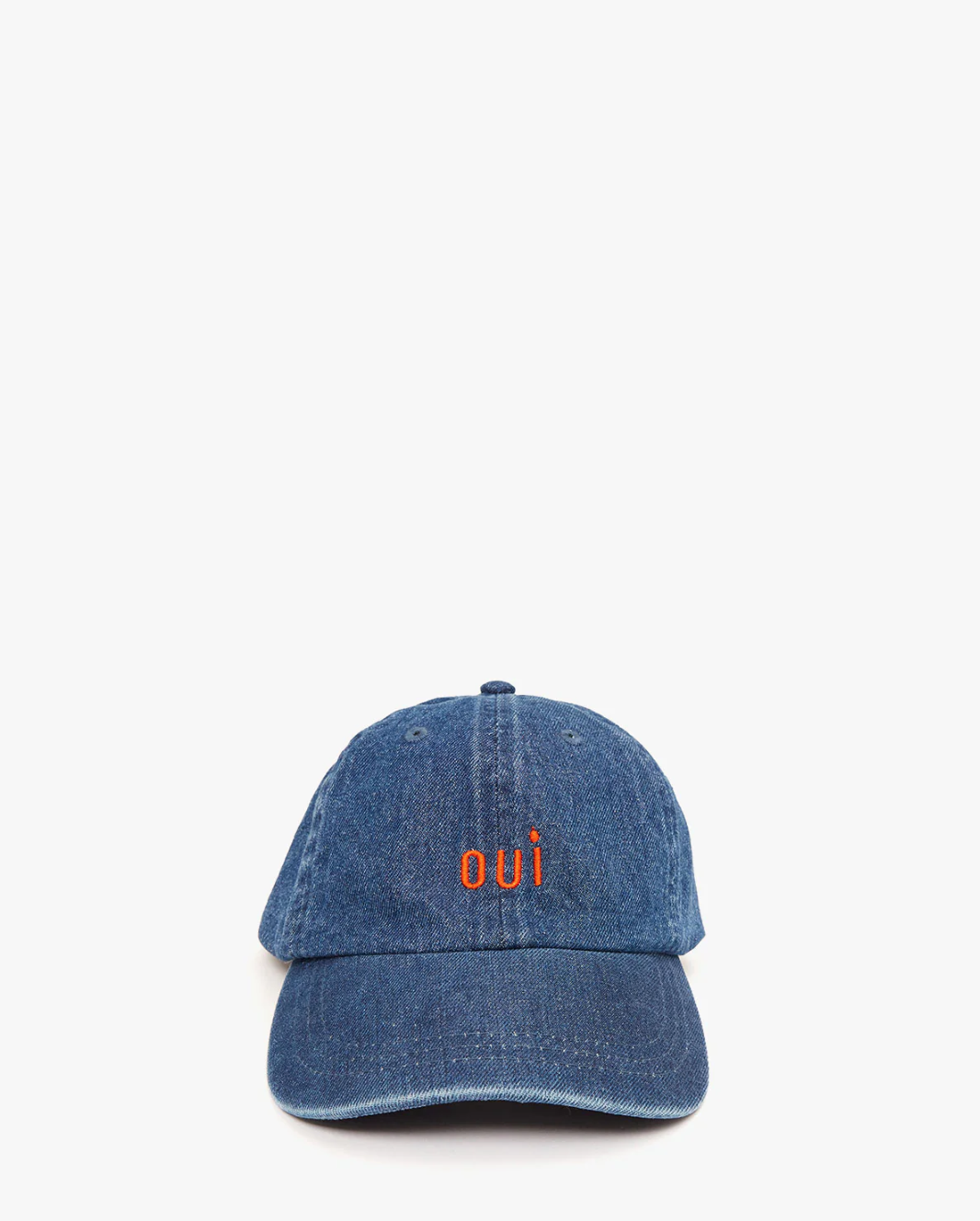 A blue denim baseball hat from Clare Vivier with the word &quot;oui&quot; embroidered in orange on the front. This adjustable cap is positioned against a plain white background.