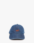 A blue denim baseball hat from Clare Vivier with the word "oui" embroidered in orange on the front. This adjustable cap is positioned against a plain white background.