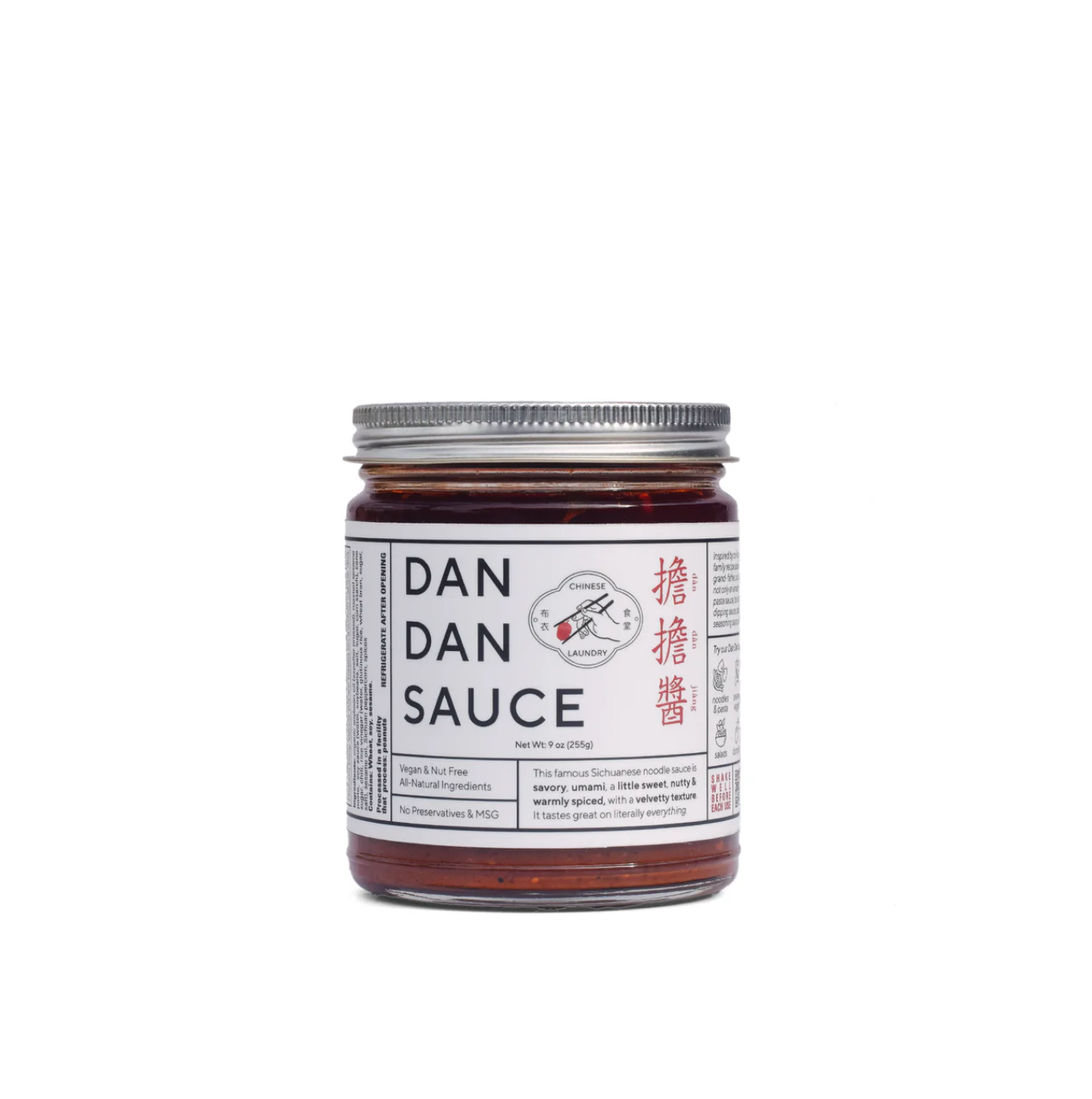 A jar of Faire Sichuan Spicy Dan Dan Sauce with a silver lid and a white label. The label features text in English and Chinese characters, along with the image of a red chili pepper and a white hand holding a pair of chopsticks, promising rich umami flavor perfect for any Chinese noodle dish.