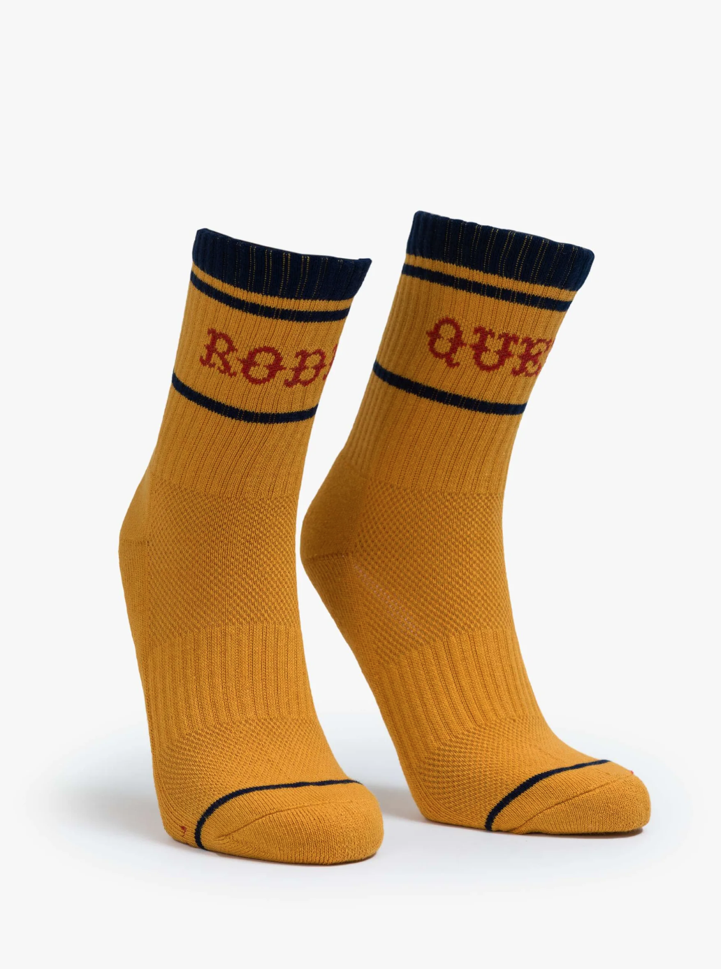 These Baby Steps tube socks by Mother boast a classic mustard-yellow design with bold black toes and cuffs. A black stripe accentuates the top, while one sock displays "ROB" and the other "OUR" in eye-catching red lettering, making them perfect for unleashing your inner Rodeo Queen.