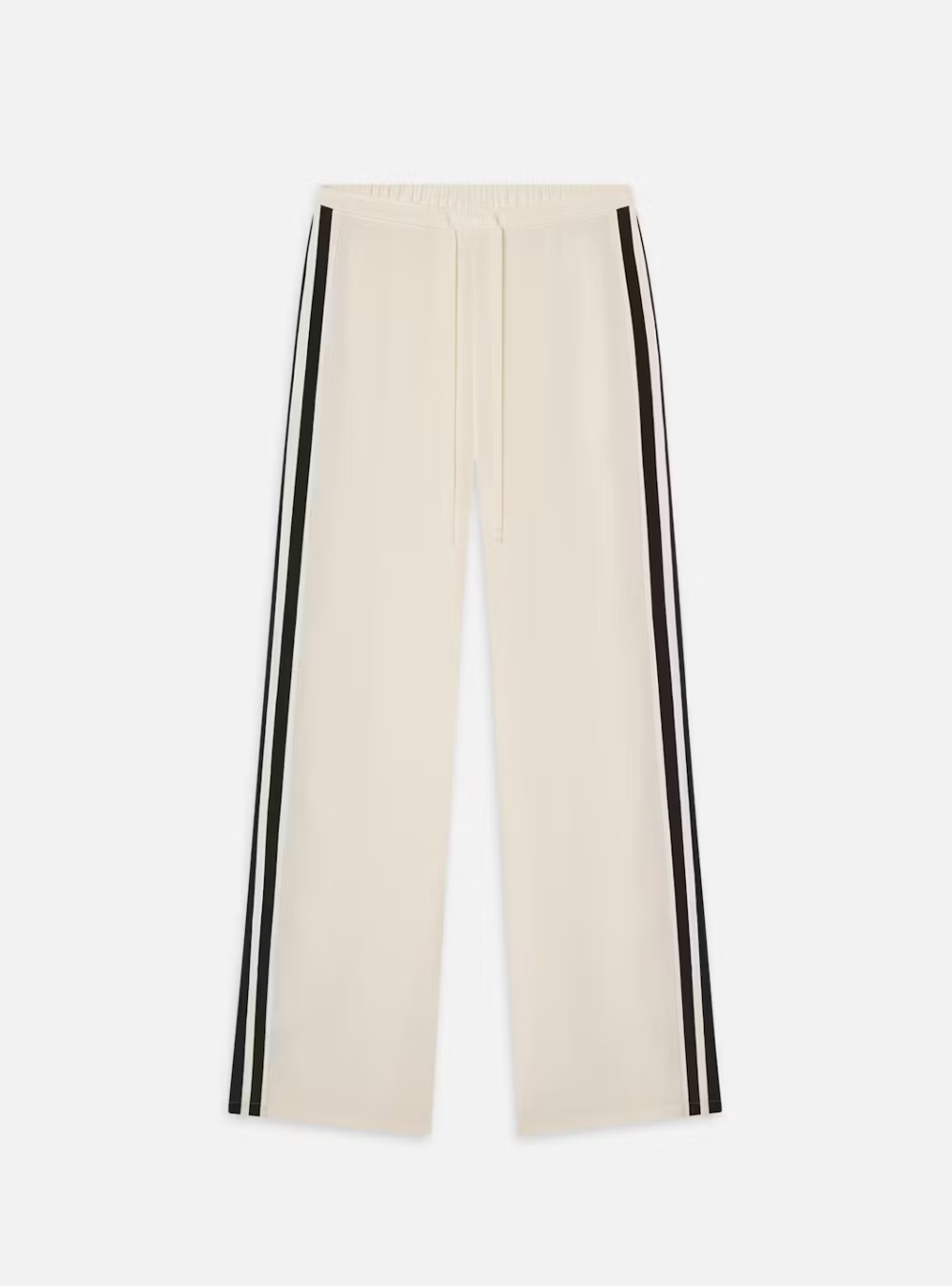 The Silk Pajama Pant by FRAME features a beige wide-leg silk design with a fluid silhouette, drawstring waist, and two black side stripes. It is displayed laid flat against a white background.