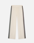 The Silk Pajama Pant by FRAME features a beige wide-leg silk design with a fluid silhouette, drawstring waist, and two black side stripes. It is displayed laid flat against a white background.