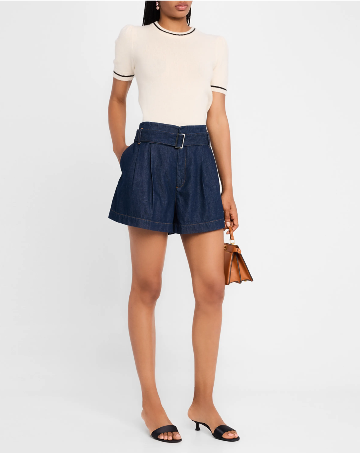 Dressed in a short-sleeve white top and stylish FRAME's Paper Bag Shorts, they've paired the look with a small brown handbag and black heeled sandals against a plain white backdrop.