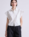 A person with short brown hair wears the Apiece Apart Toni Sleeveless Top in white and black wide-leg pants, standing against a plain light background.