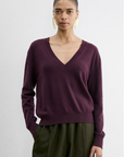 Rachel Comey Slate Pullover in burgundy styled with olive pants and gold earrings, white background.