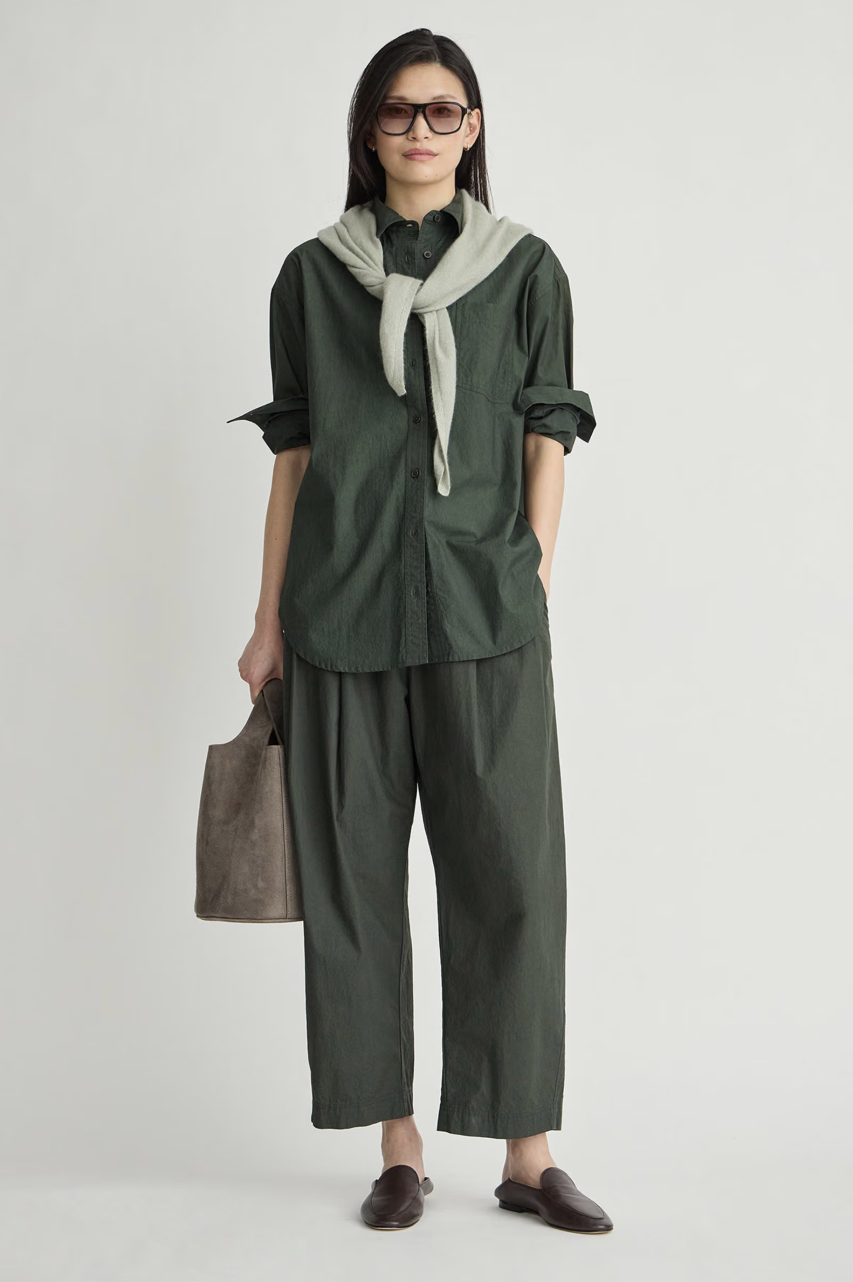 Apiece Apart oversized button down styled with a gray sweater, tote bag, brown shoes, and sunglasses for a relaxed look.