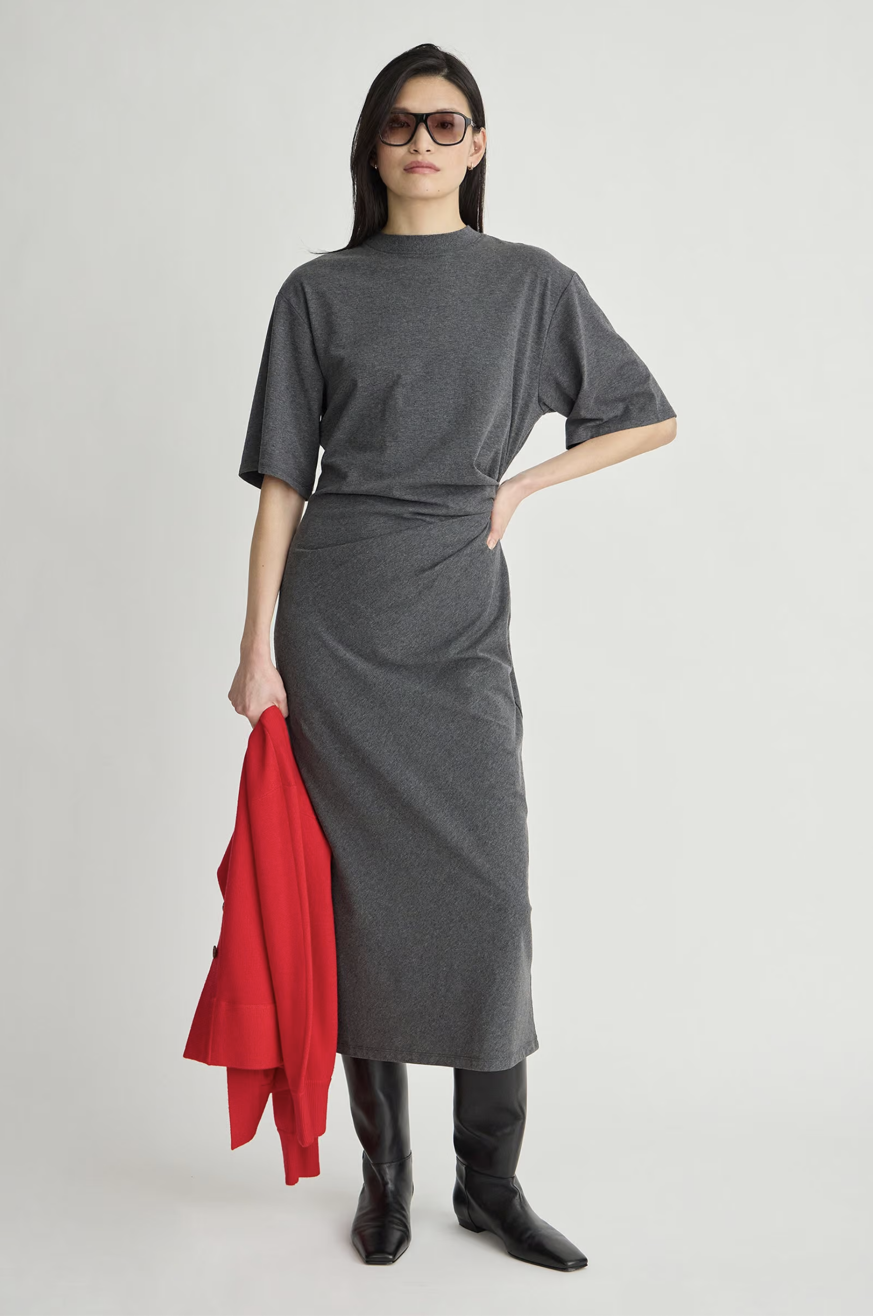 Luna Cinched Maxi dress by Apiece Apart styled with black boots and sunglasses, red coat in hand, neutral backdrop.