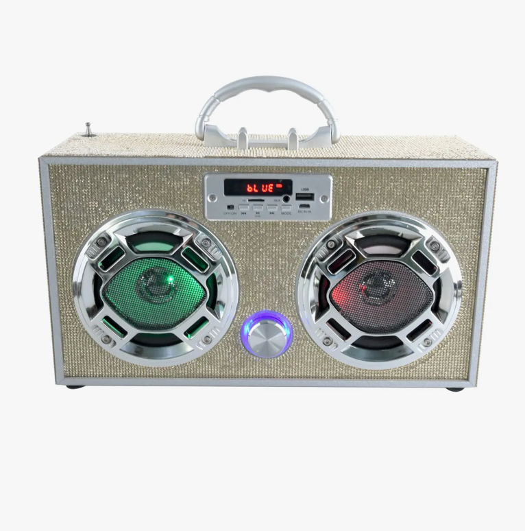 A Gold Bling Wireless Boombox with Fm Radio by Trend Tech Brands/wireless features a textured beige exterior, two circular speakers emitting colorful LED lights in green and red, and a silver handle on top. The control panel includes a small display reading "bt USE" alongside various buttons and ports.