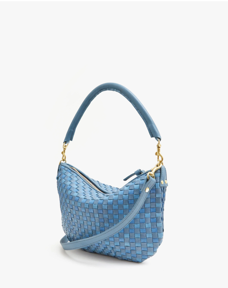 A Petit Moyen Woven Checker by Clare Vivier with a handwoven design and gold hardware. It features a top handle and a zip-top main compartment. The bag's structure is soft and slightly curved, giving it a relaxed yet stylish appearance, reminiscent of a chic mini messenger.