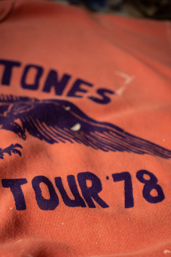 Close-up of a red vintage Shrunken Sweat T-shirt featuring "Stones Tour 78" in bold letters with a graphic design, focused on the text and graphic details in Scottsdale, Arizona. (Made Worn)