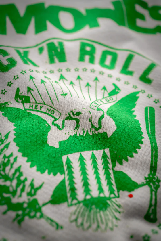 Close-up of a green and white Made Worn shrunken sweat featuring the phrase "MONSTERS OF ROCK 'N' ROLL" and an eagle motif surrounded by bungalows and stars.