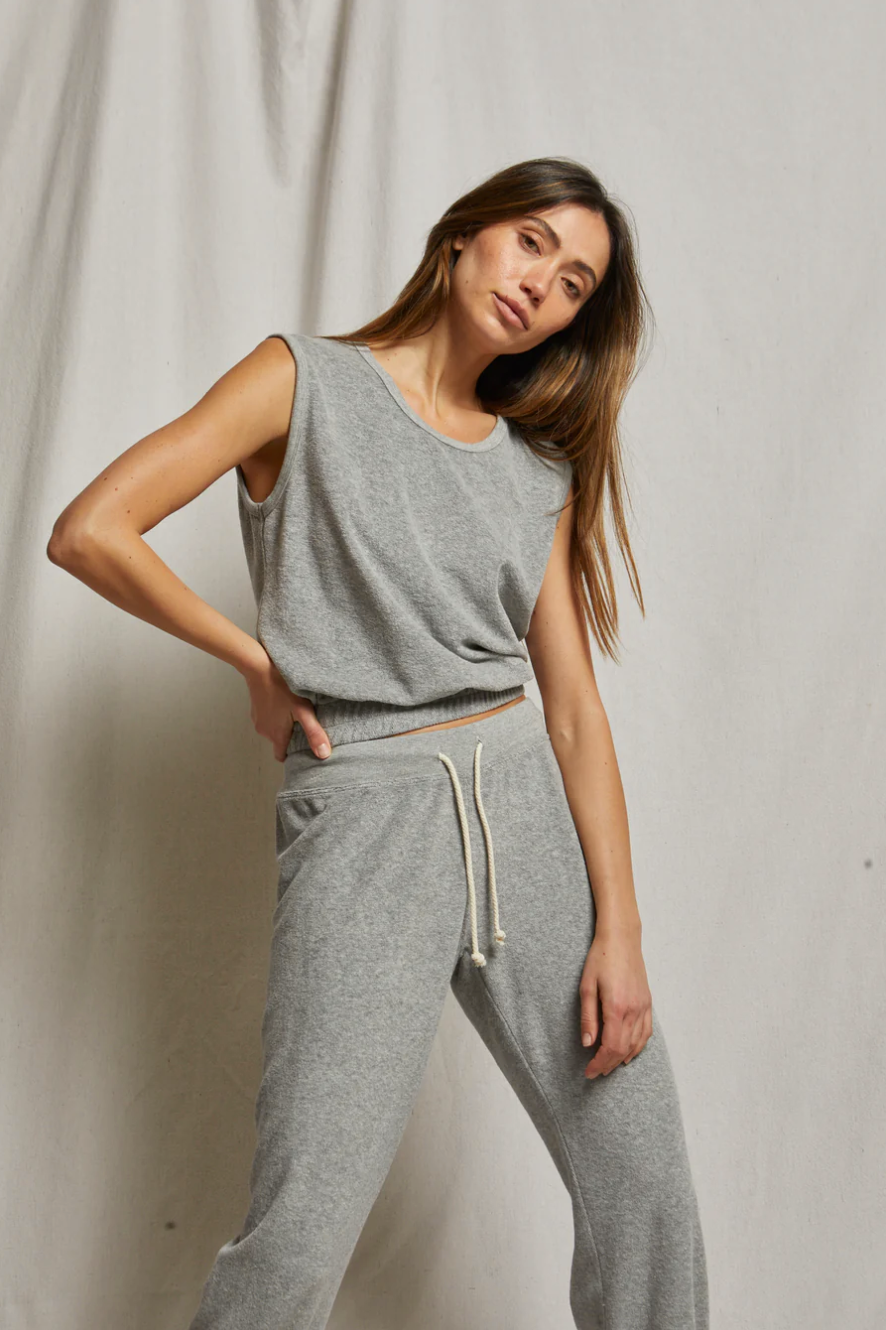 A woman poses against a light backdrop in Perfectwhitetee&#39;s ELLIE terry banded tank and matching gray sweatpants, featuring a scoop neckline and drawstring waist, looking at the camera with a relaxed expression.