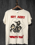 A cream-colored T-shirt with "KISS ARMY WANTS YOU!" printed on it, featuring an illustration of the band members from KISS in a cloud-like outline, hanging on a rustic wooden wall in a bungalow-style room by Made Worn.