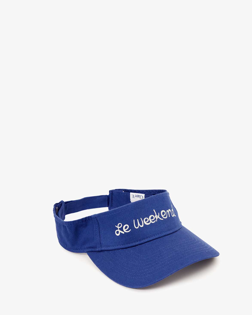 A royal blue Visor with the phrase &quot;Le Weekend&quot; embroidered in white cursive on the front. Made from 100% cotton, this cap by Clare Vivier features a Velcro closure for easy adjustment. It&#39;s displayed against a plain white background.