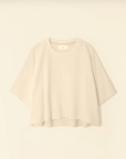 A light beige, oversized Romeo Sweatshirt by Xirena, featuring a round neckline and raw edge elbow sleeves, displayed on a plain background. The sweatshirt boasts a relaxed, boxy fit with a slightly curved and uneven hem for added style.